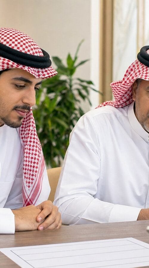 متدرب سعودي وولي أمره يراجعان معلومات التسجيل في دبلوم مهني داخل أكاديمية تدريب بالرياض